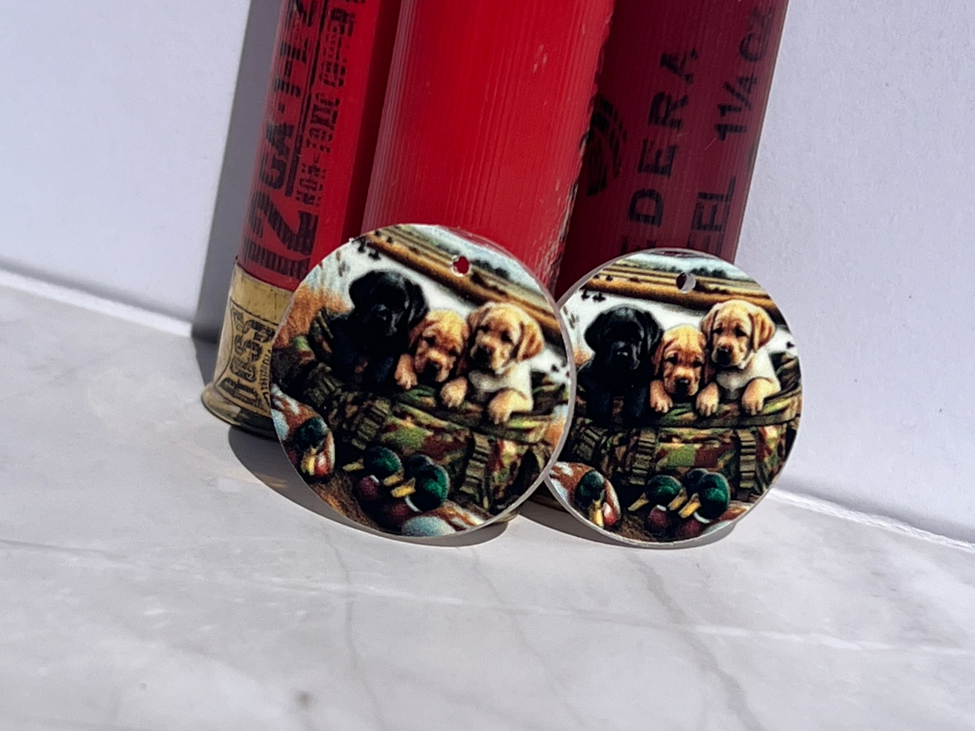 Pair of earrings with three lab puppies with ducks design on a white surface