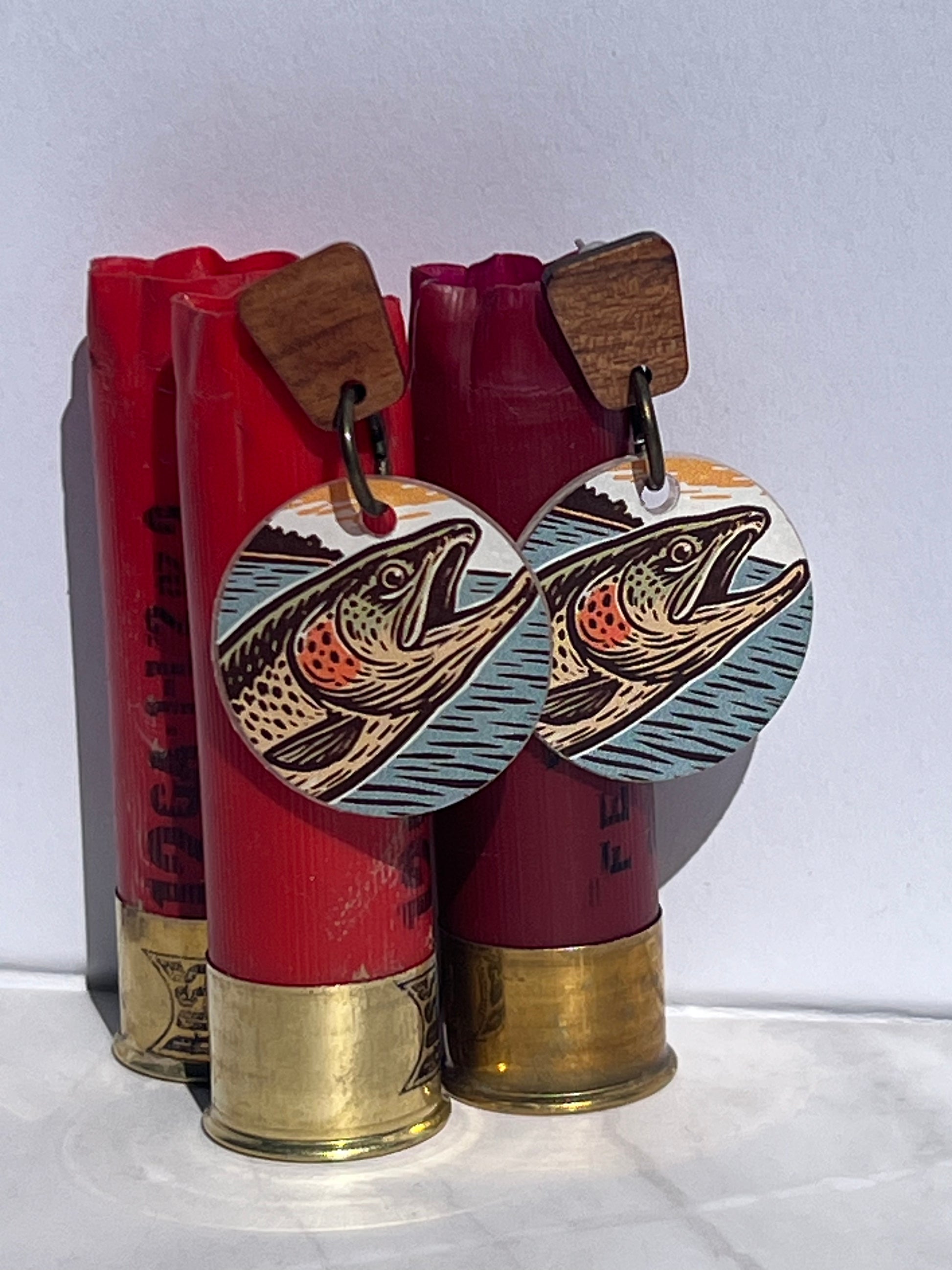 Fish-themed earrings displayed on red shotgun shells with a white background