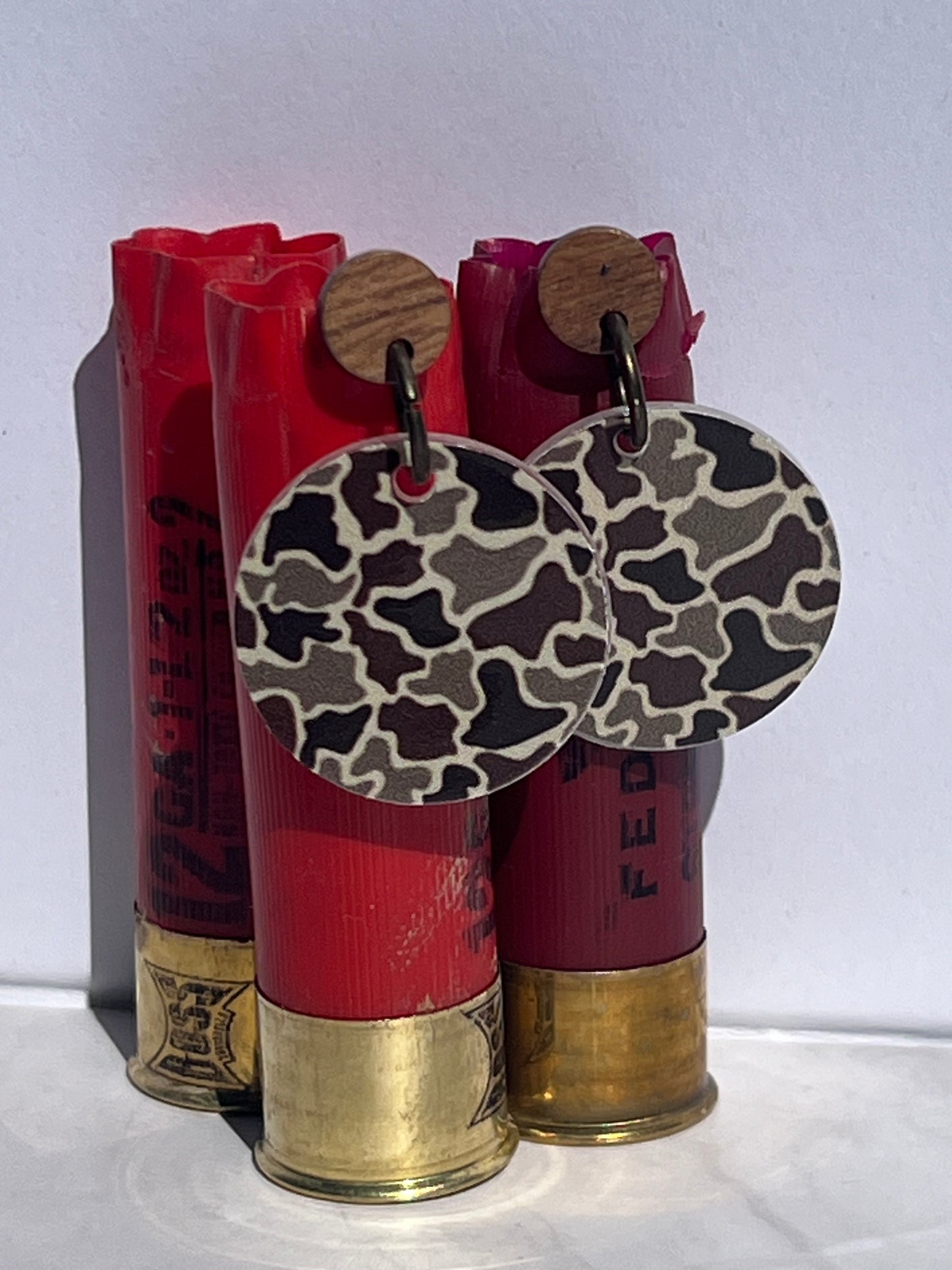 old duck camo print earrings displayed on red shotgun shells against a white background